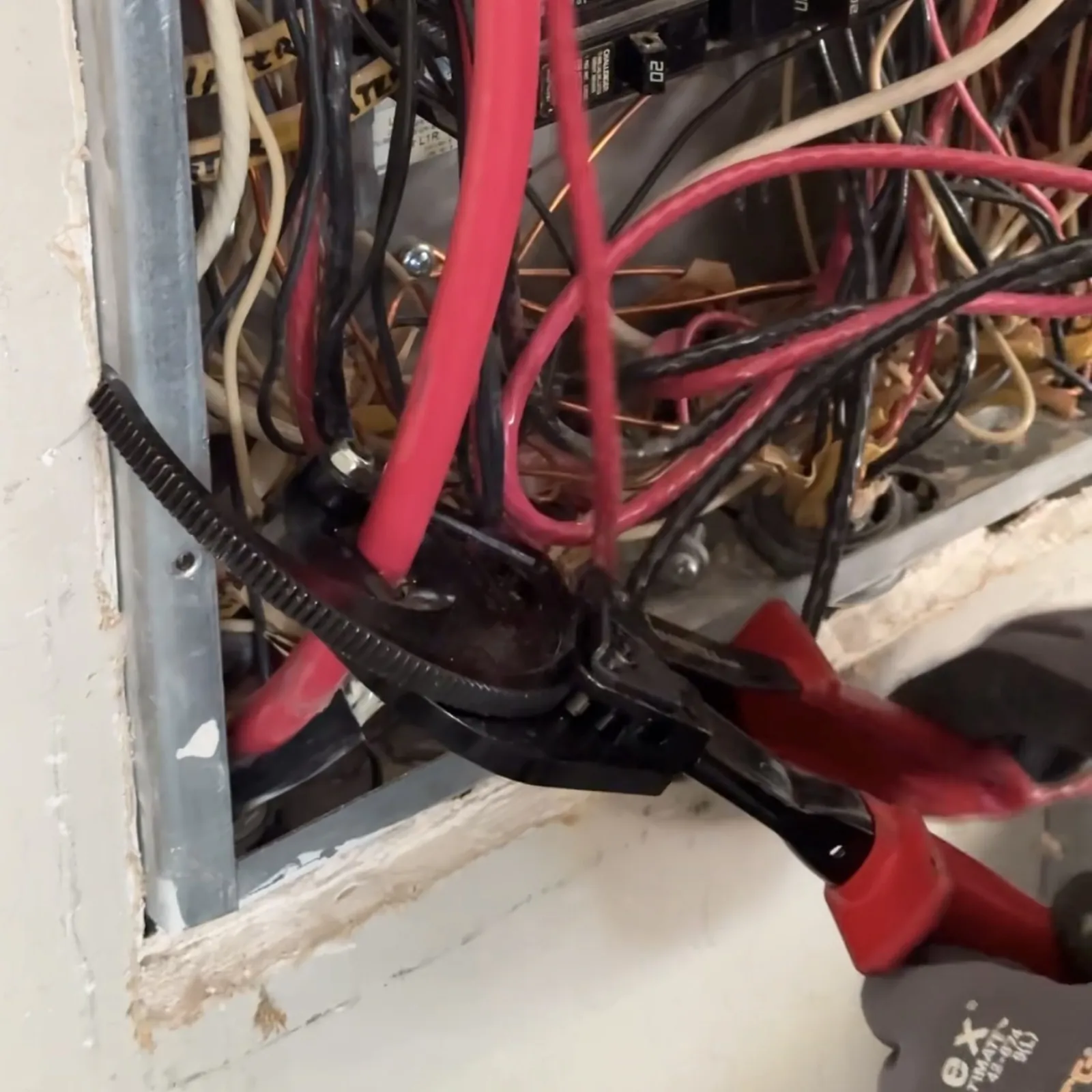 Electrician cutting out a damaged section of a service conductor inside an electrical panel in a San Jose home