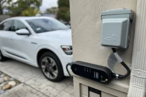 Portable EV charger plugged into a new outdoor EV charger outlet next to a parked electric car in San Jose