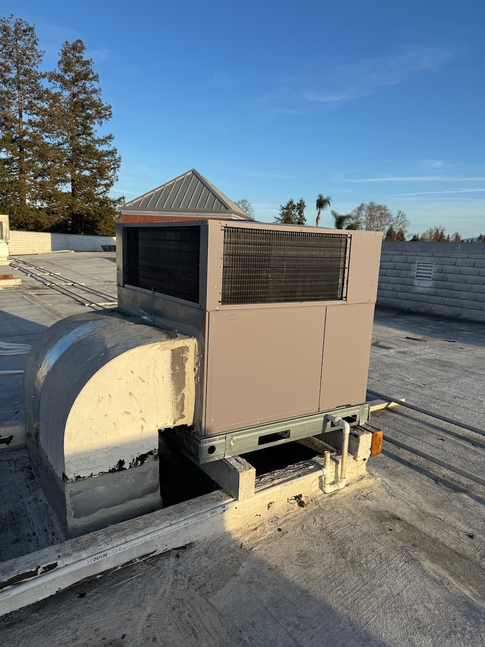 A packaged HVAC unit and ductwork on the roof of a commercial property
