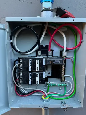 Open electrical enclosure with circuit breakers and red black white and green conductors