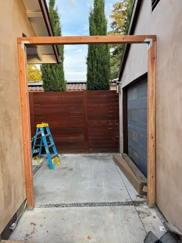 Timber framing and ladder in a narrow exterior space beside a house