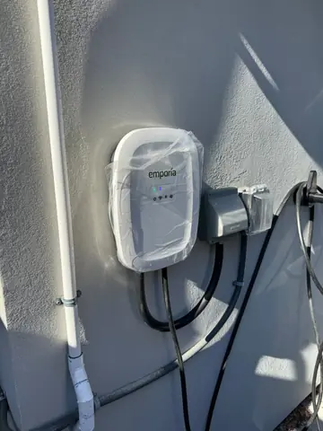 Electrical meter enclosure and adjacent wiring mounted on an exterior wall