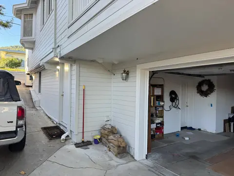 House and open garage with exterior electrical equipment and surface-mounted conduit