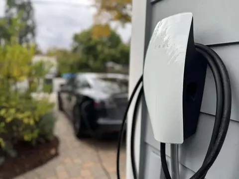 Tesla Wall Connector with its charging cable coiled beside a driveway